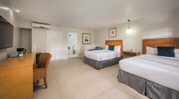 A hotel room with two beds, a desk with a coffee maker, a chair, and a wardrobe.