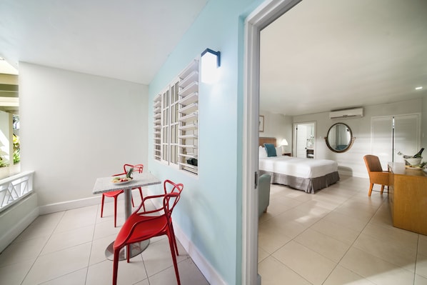 Une chambre d’hôtel moderne équipée d’un lit, d’un bureau et d’un coin repas avec des chaises rouges.