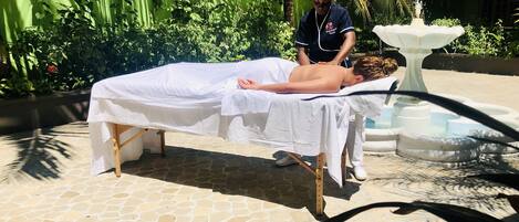 Une séance de massage en plein air, dans un jardin, avec un sol en pierre et une fontaine.