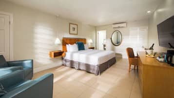 A hotel room with a bed, a desk with a coffee maker, a TV, and a chair.
