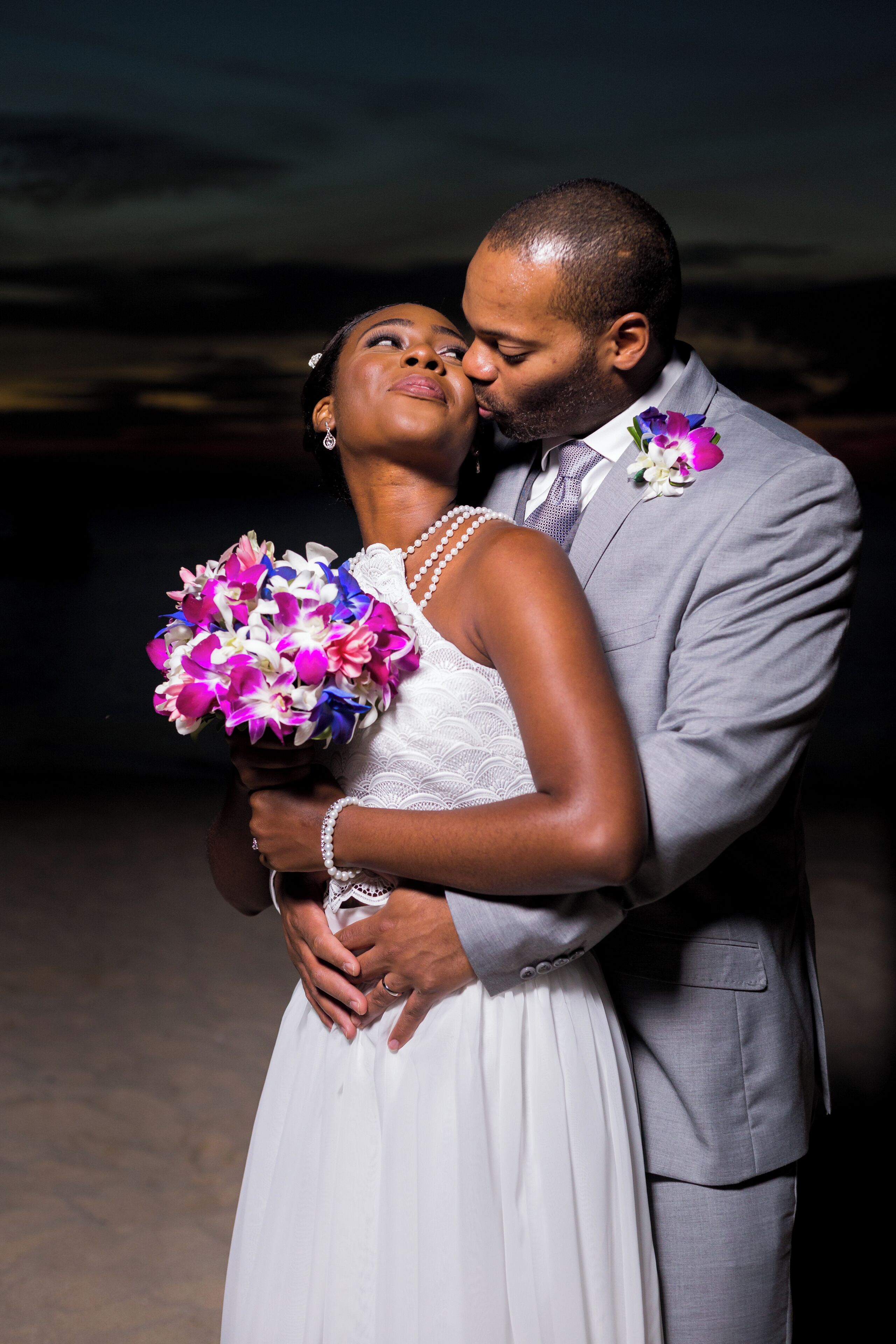 A couple embracing, with the woman holding a bouquet of flowers.