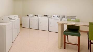 A laundry room with multiple washing machines and a table with chairs.