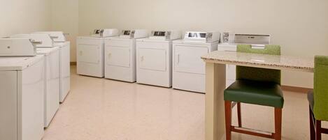A laundry room with multiple washing machines and a table with chairs.