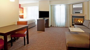 Een hotelkamer met een bed, een televisie, een bureau, een bank en een open haard.
