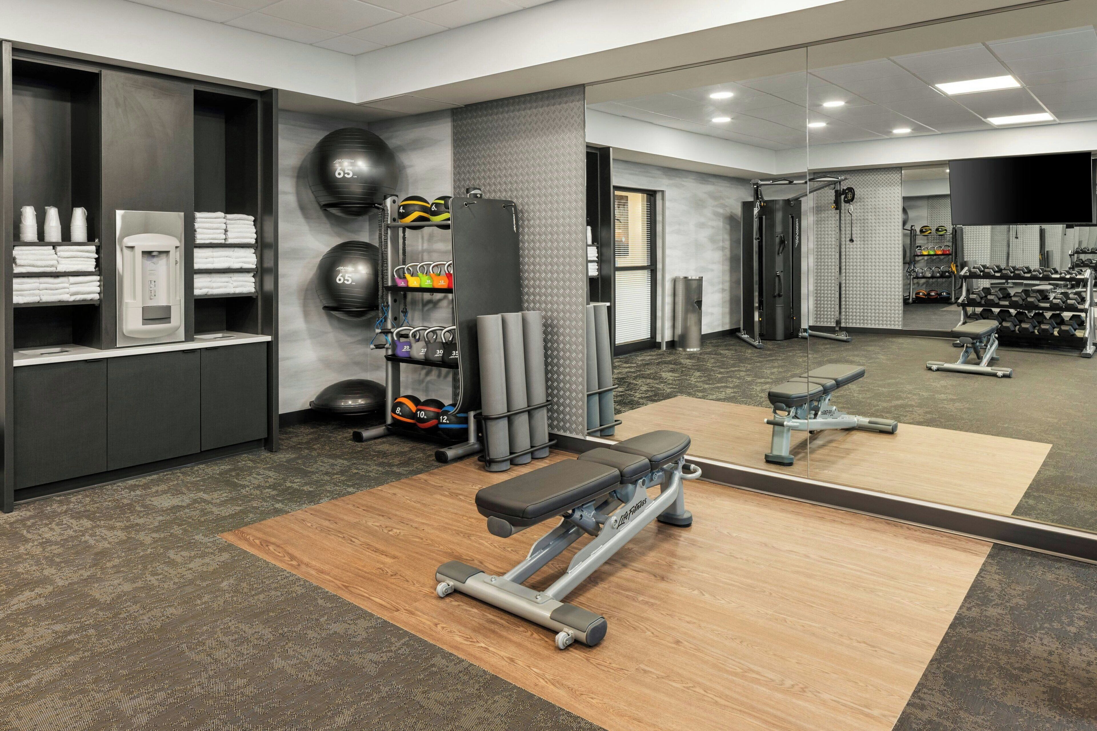 A gym with exercise equipment, towels, and a mirror.