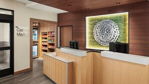 Una zona de recepción con mostradores de madera, un gran elemento decorativo en la pared y estantes llenos de aperitivos.