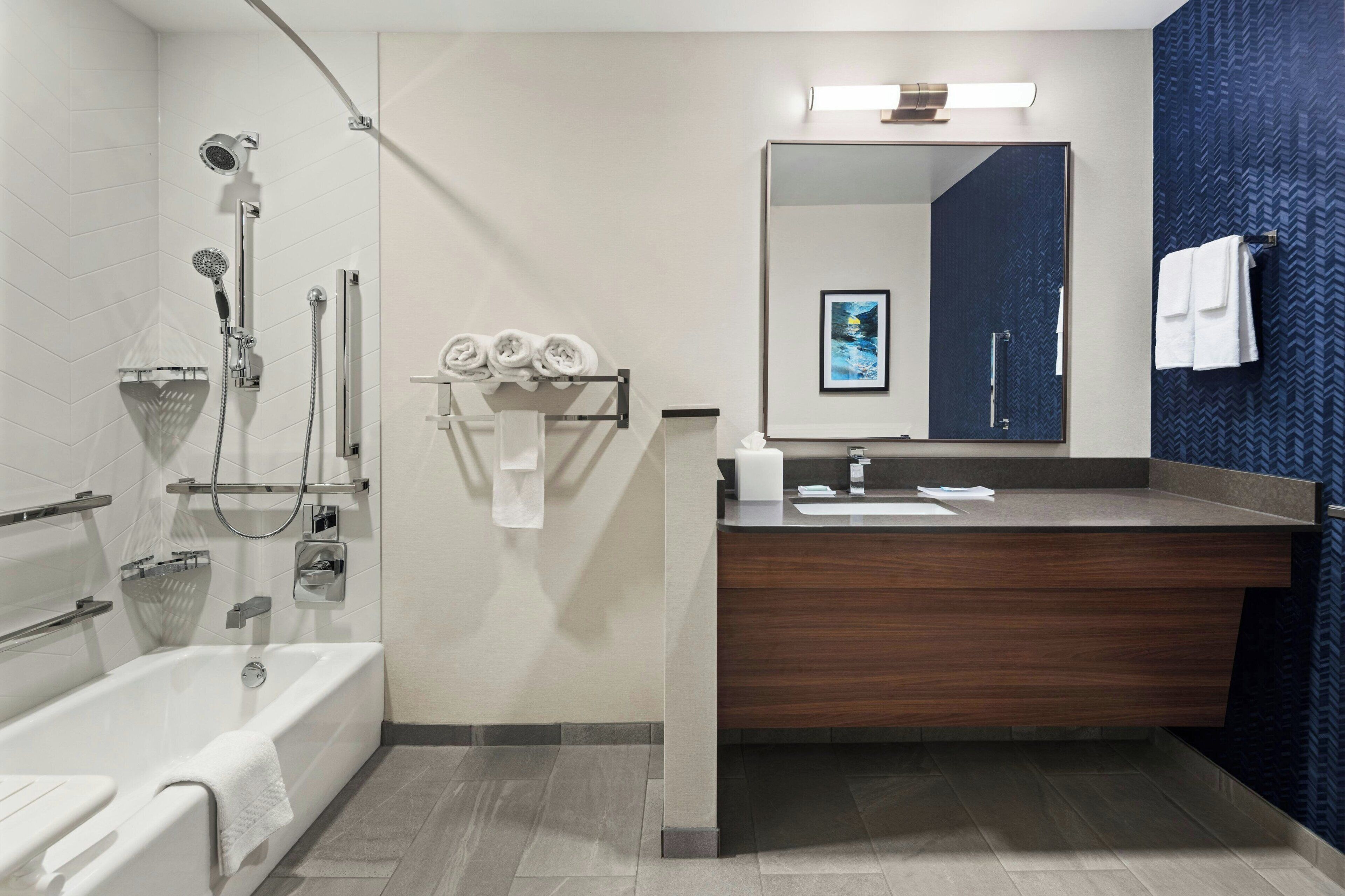 A modern bathroom with a bathtub, shower, and vanity.