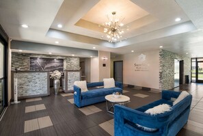 Welcome to our hotel lobby, featuring a reception desk, comfortable seating area, and a stunning abstract art piece.