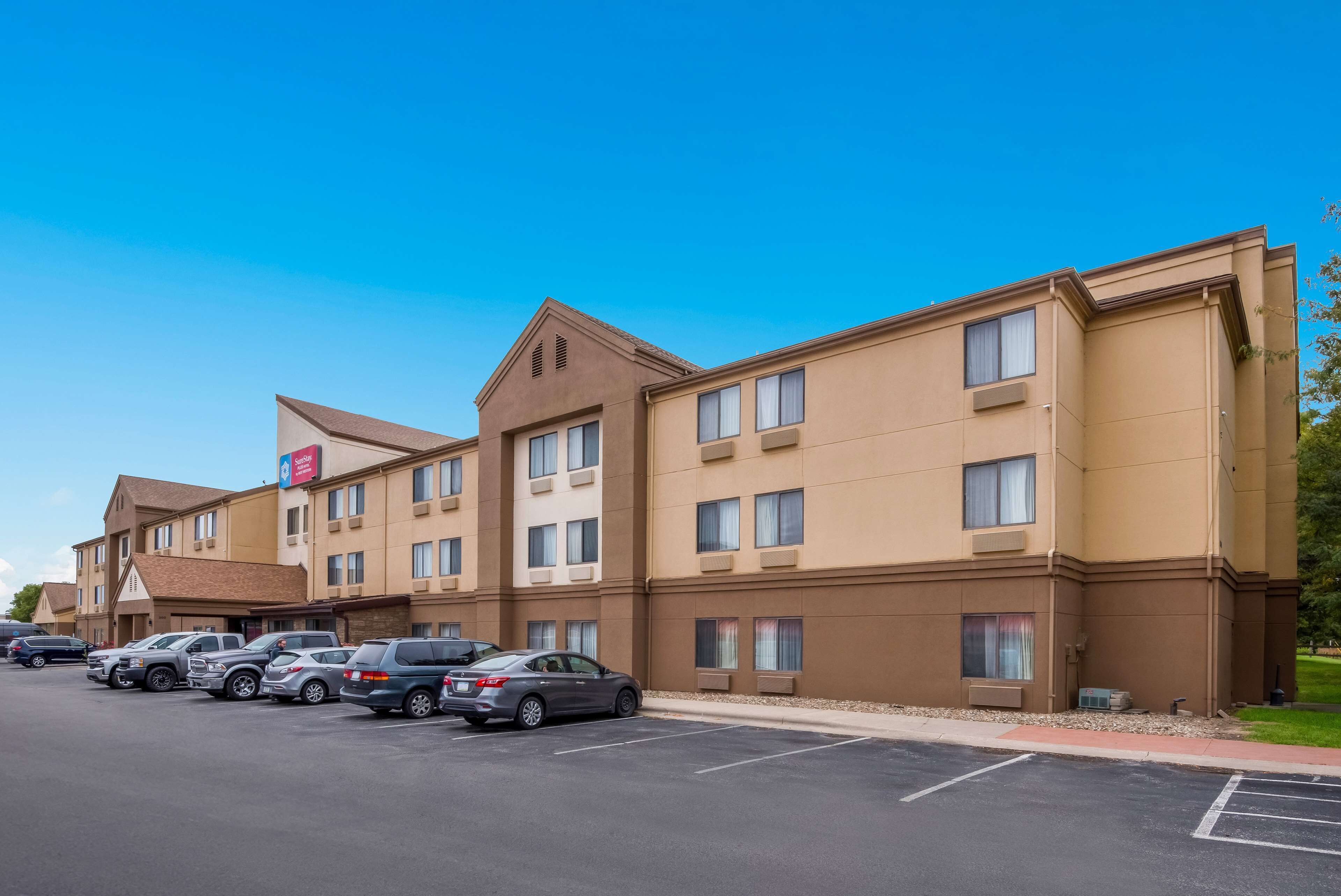 A hotel with multiple floors, a parking lot, and a clear blue sky.