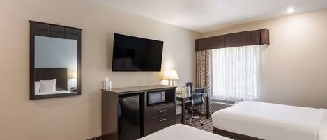 A hotel room with two beds, a desk, a television, a mirror, and a window with curtains.