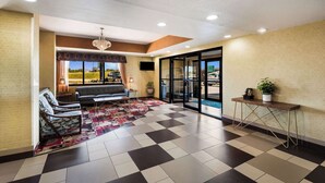 A lobby with a checkered floor, a sofa, chairs, a chandelier, a plant, and a view through the glass doors. - Quality Inn Des Moines North (Des Moines)