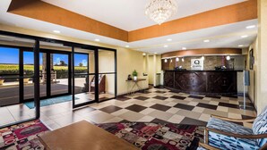 A hotel lobby with a checkered floor, a reception desk, a chandelier, and a view through the glass doors. - Quality Inn Des Moines North (Des Moines)