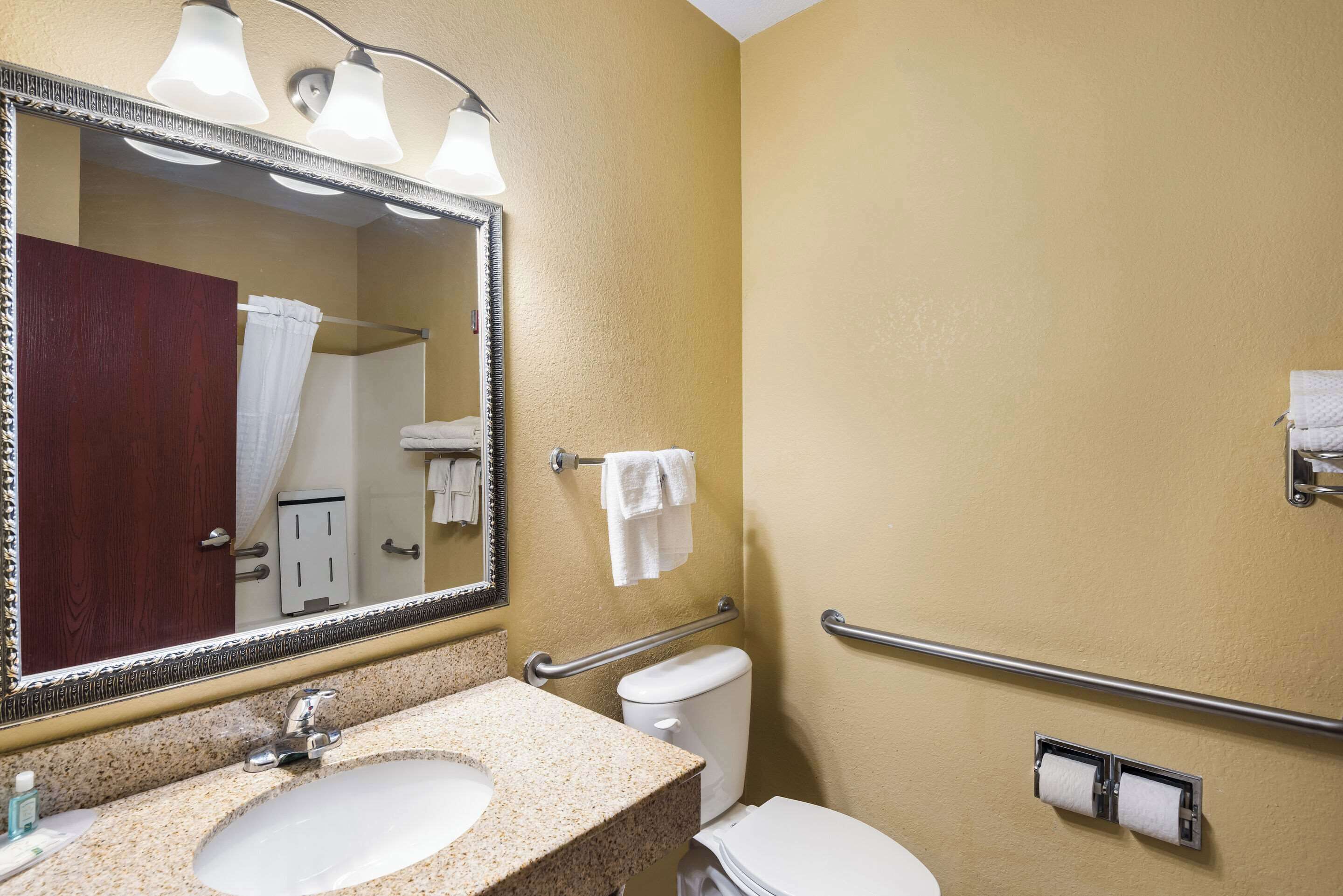 A bathroom with a sink, mirror, towel rack, and toilet.