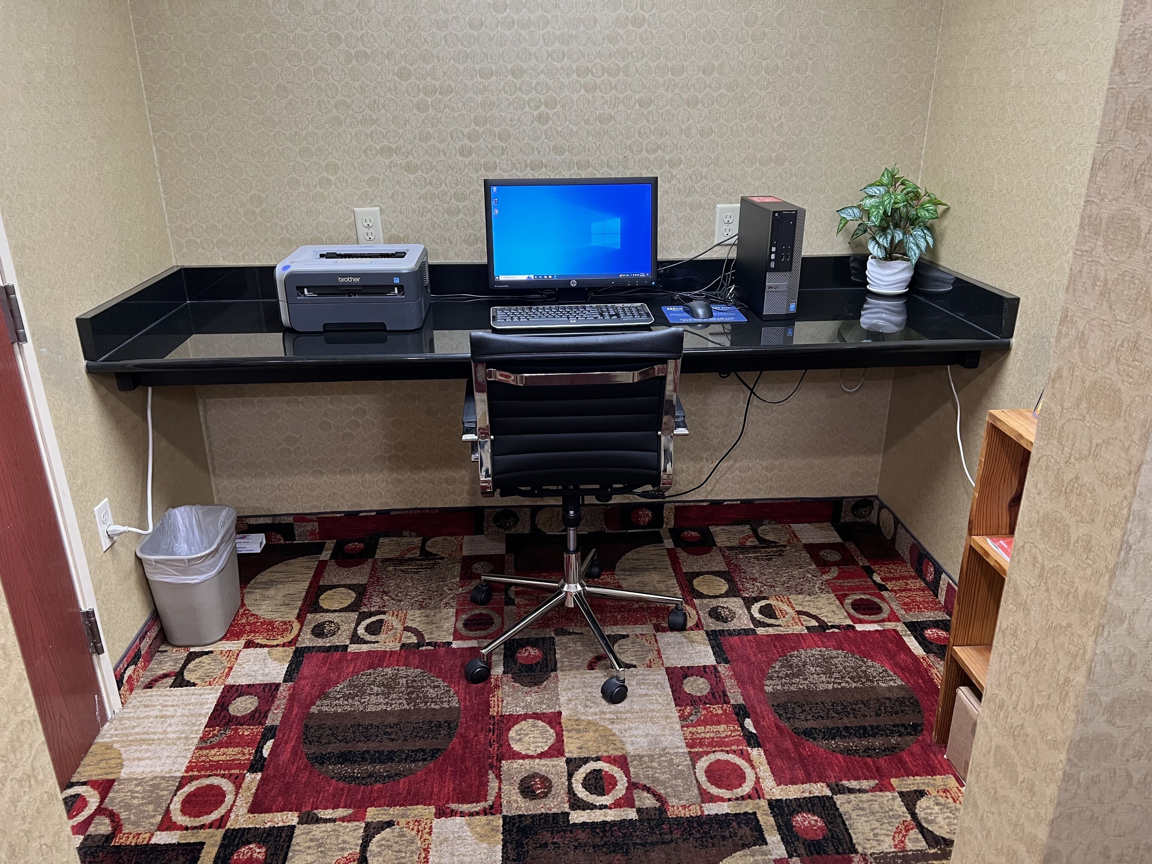 A compact office space with a desk, chair, printer, computer, and a small potted plant.