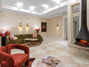 A living room with a fireplace, a sofa, a red chair, and a coffee table.