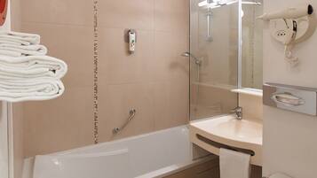 A modern bathroom with a bathtub, a sink, a toilet, and a hairdryer mounted on the wall.