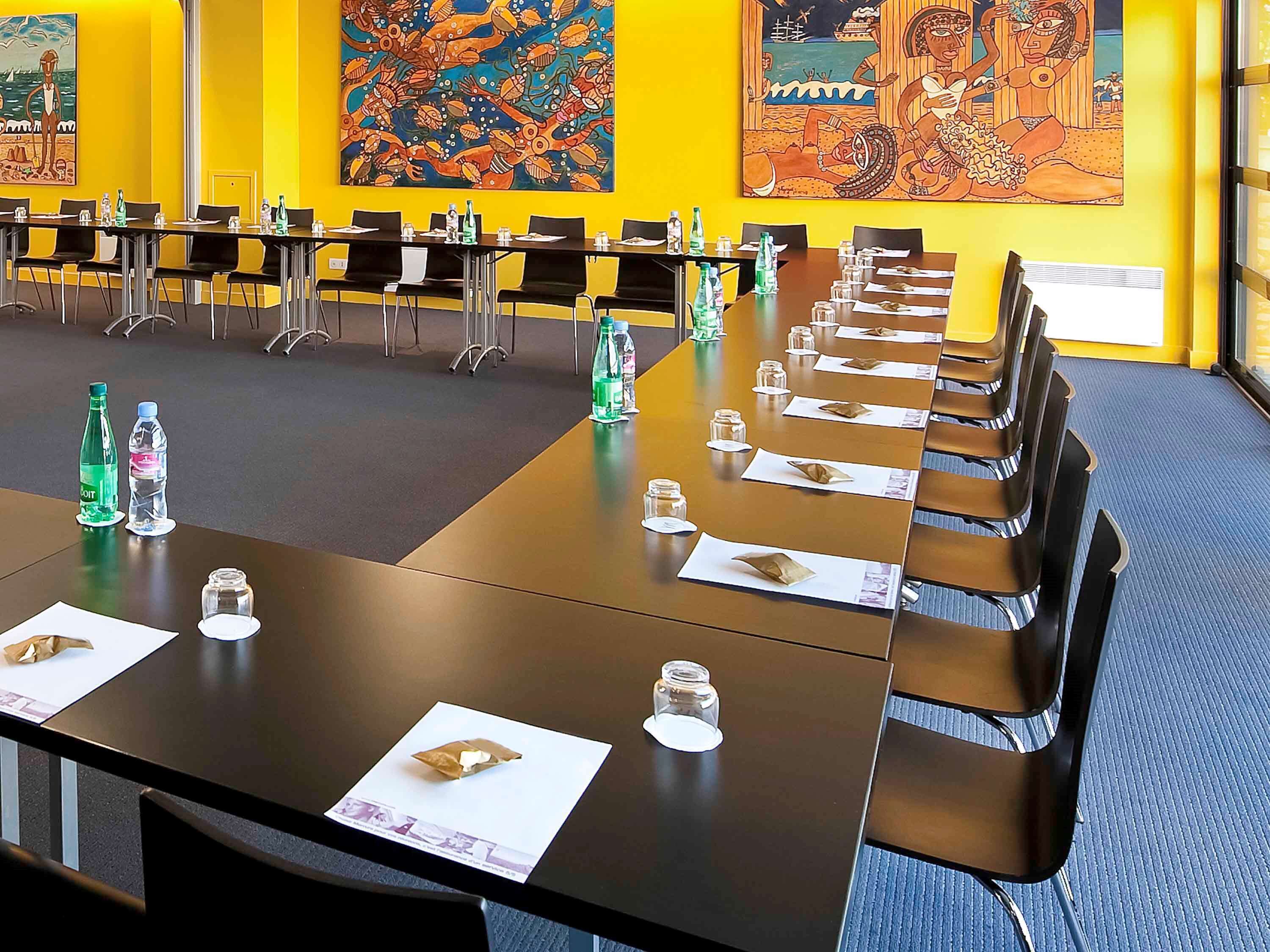 A conference room with a long table, chairs, water bottles, and papers.