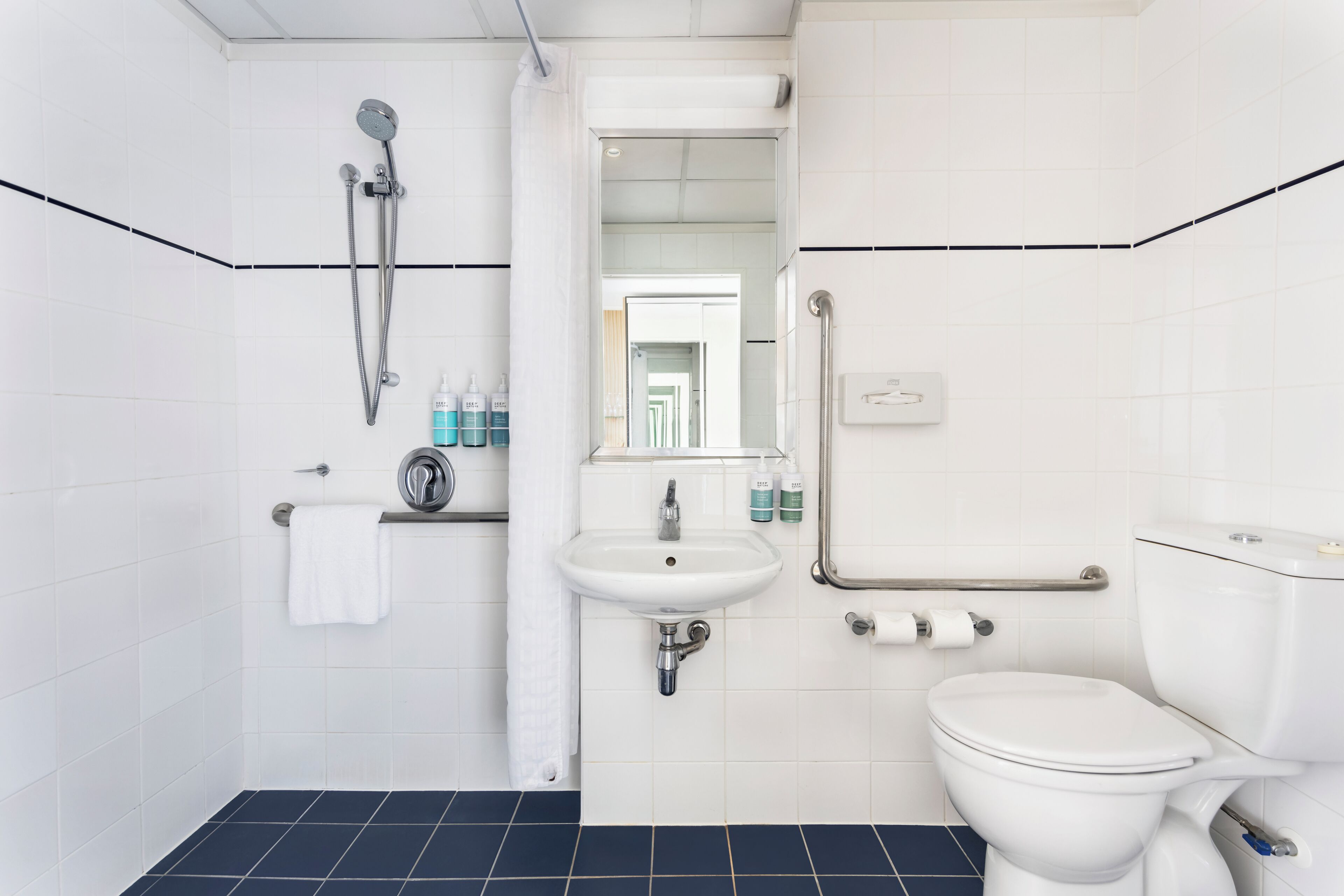 A modern bathroom with a white sink, toilet, and shower.