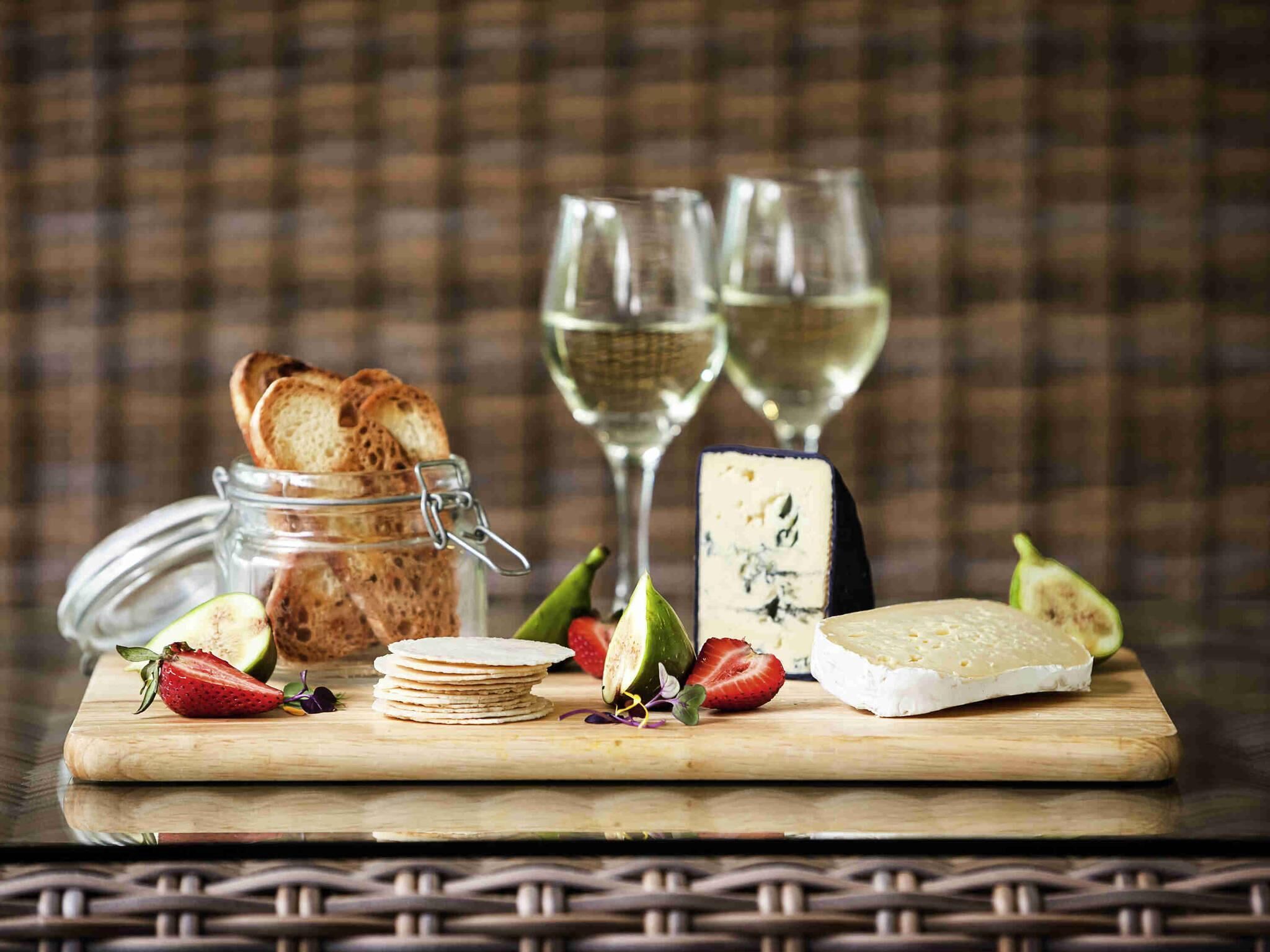 A wooden board with cheese, strawberries, and a jar of bread.