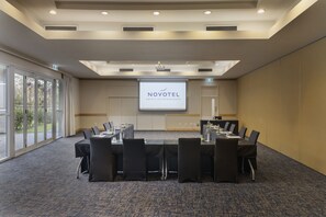 A conference room with a large screen displaying "NOVOTEL HOTELS, SUITES & RESORTS" at the front. - ibis Auckland Ellerslie (Auckland)