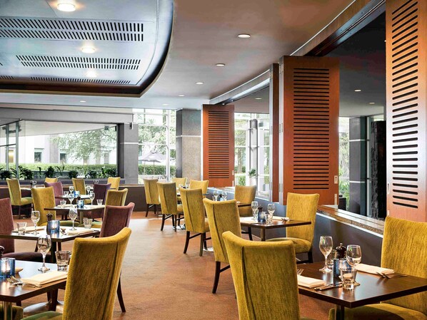 A restaurant with yellow chairs, tables set for dining, and large windows allowing natural light. - ibis Auckland Ellerslie (Auckland)