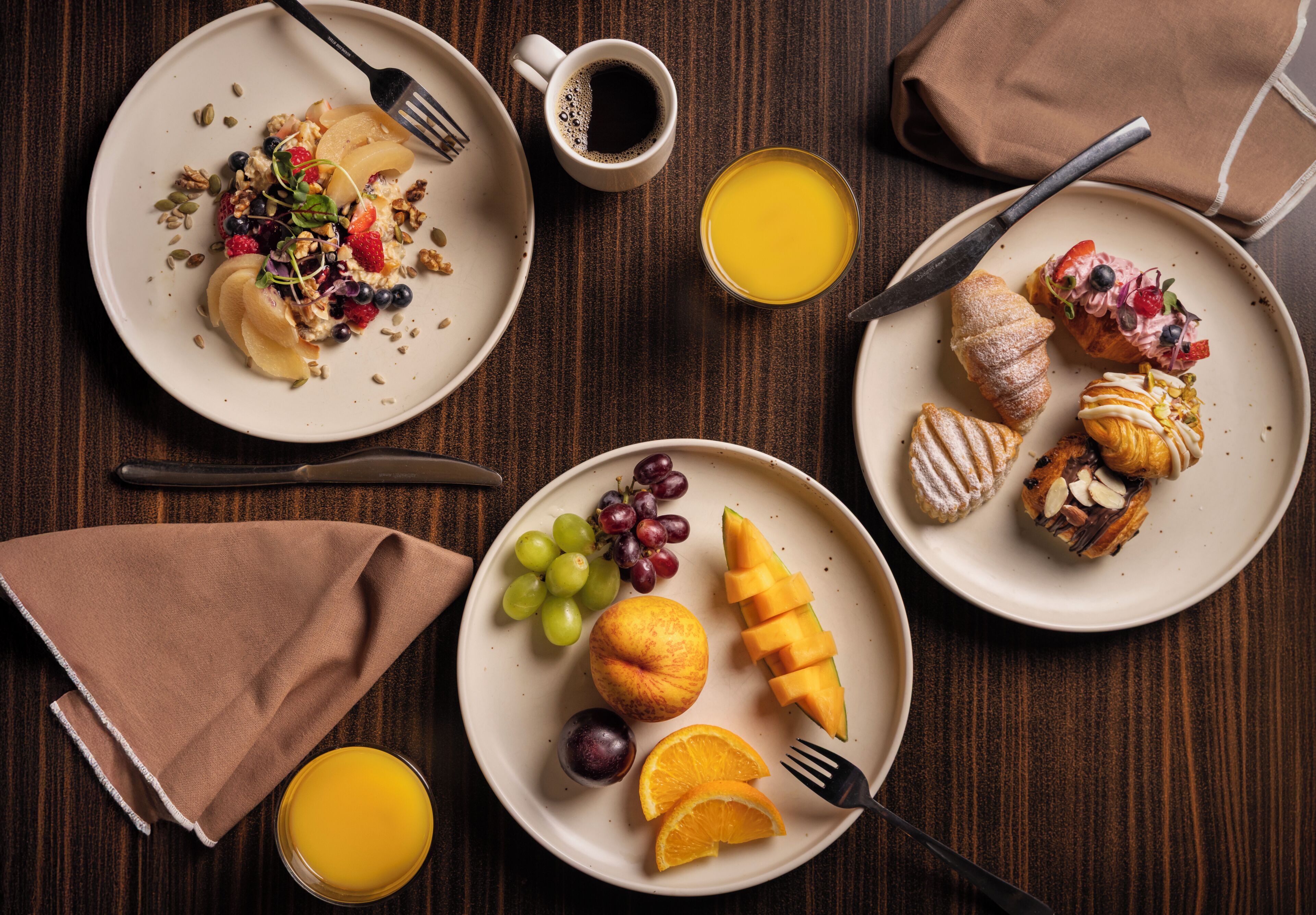 Un desayuno con platos de comida, una taza de café y un vaso de zumo de naranja.
