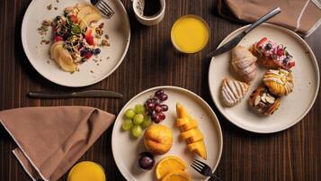 Un desayuno con platos de comida, una taza de café y un vaso de zumo de naranja.