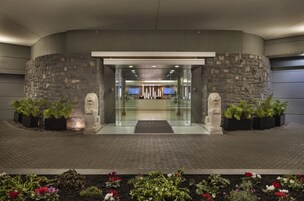 A modern building entrance with a stone facade, glass doors, and potted plants.