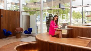 A modern interior with a curved wooden reception desk, a laptop, and a coffee cup.