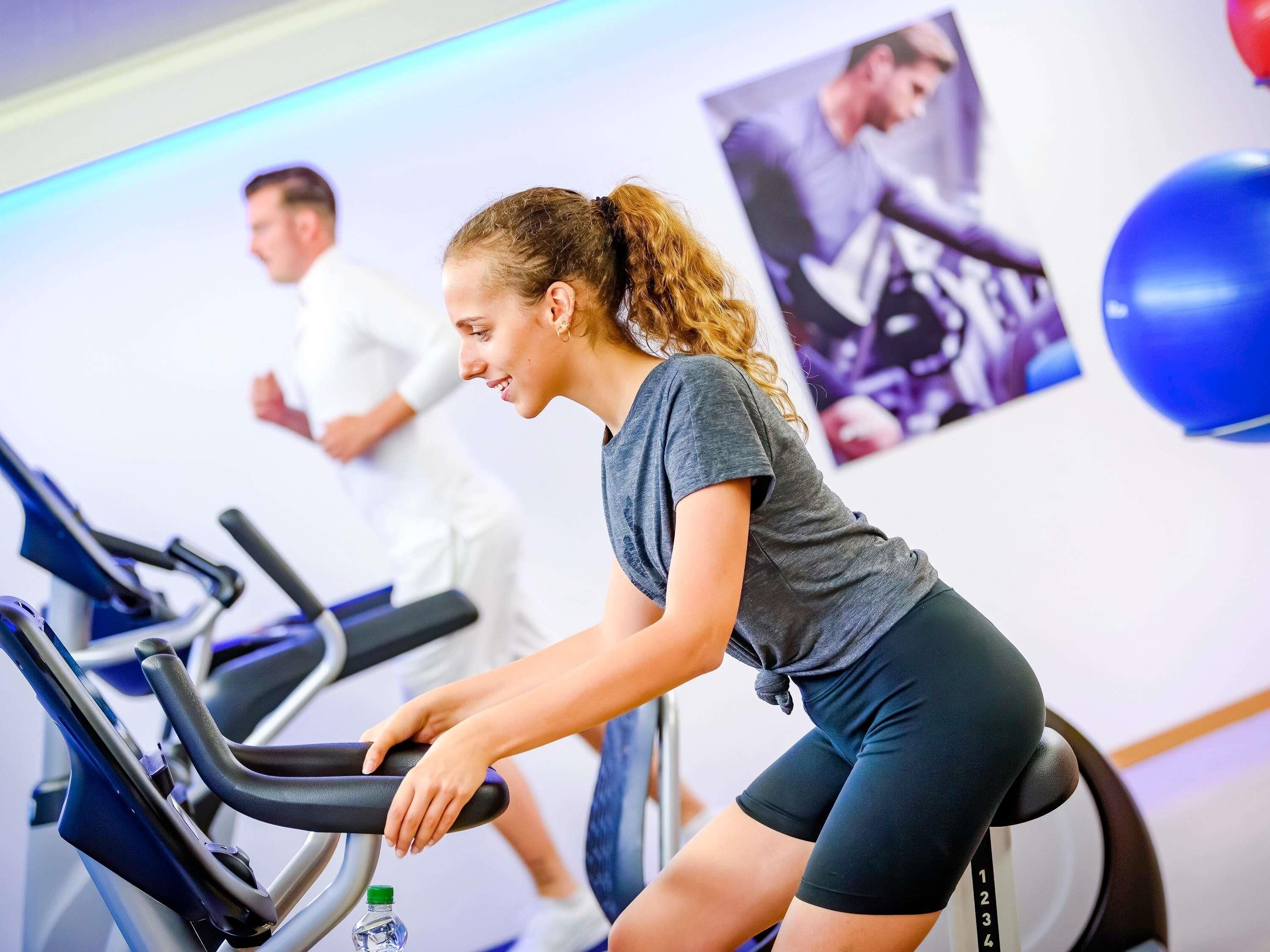 Ein Fitnessraum mit Trainingsrädern, einer Wasserflasche und einem Poster an der Wand.