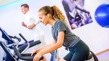 Ein Fitnessraum mit Trainingsrädern, einer Wasserflasche und einem Poster an der Wand.