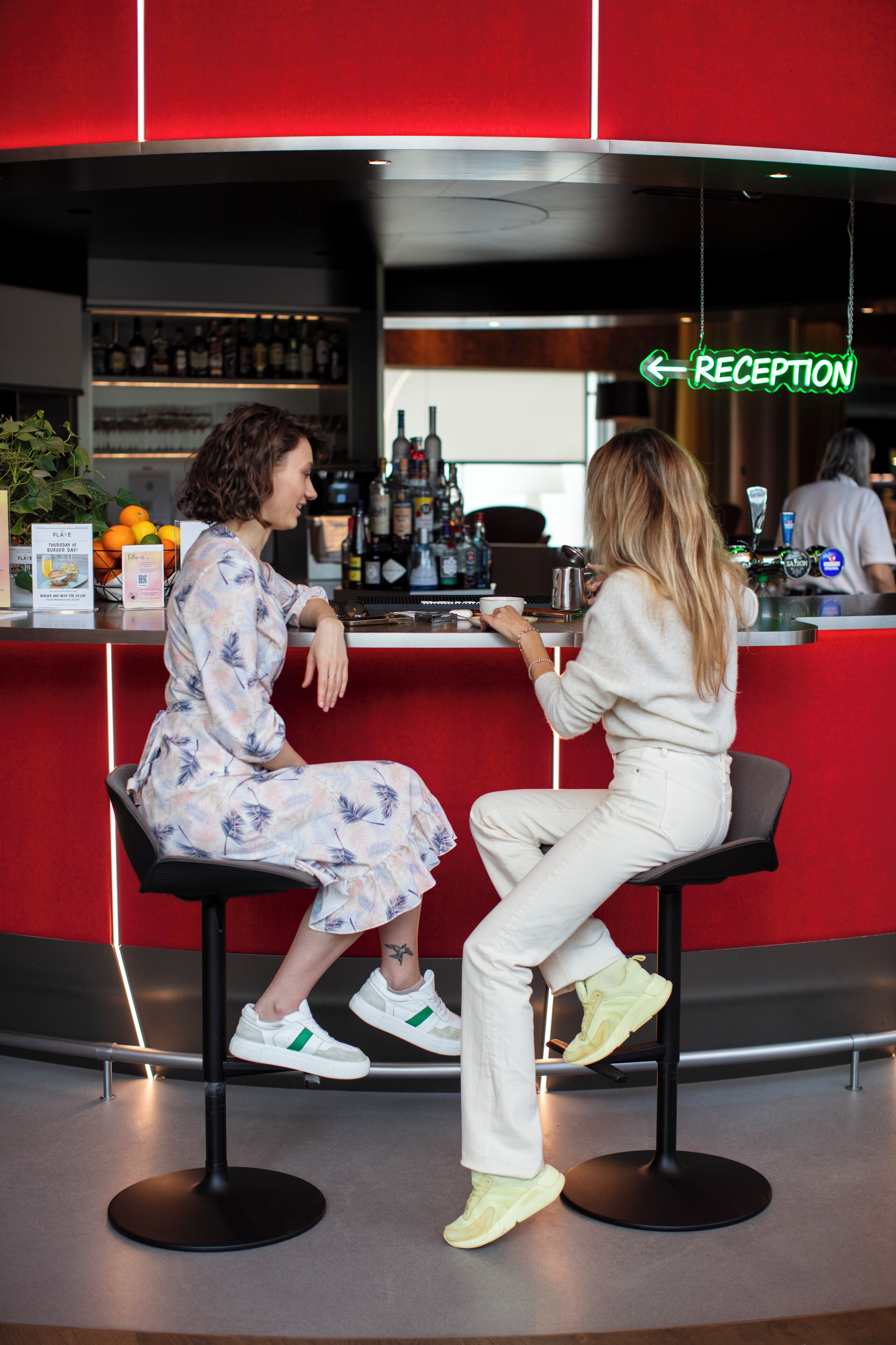 A bar area with a reception sign, bar stools, and a counter with various bottles.