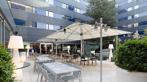 Un espace extérieur aménagé en terrasse, avec des tables, des chaises, des parasols et des plantes en pot.