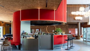 Een moderne bar met een gebogen toonbank, zitplaatsen en een grote hanglamp.