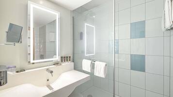 Ein modernes Badezimmer mit großem Spiegel, zwei Waschbecken und einer Duschkabine.