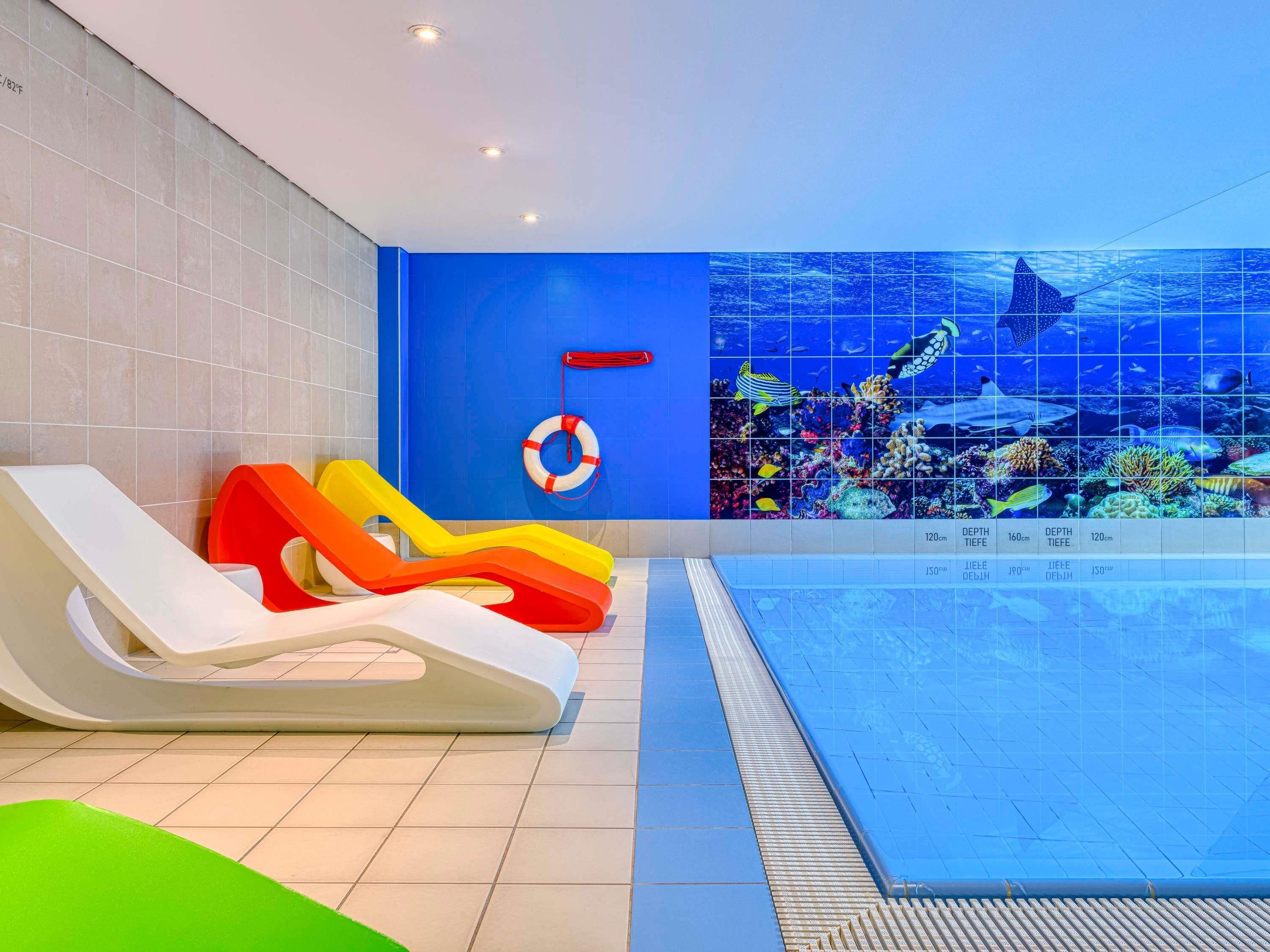 Un espace piscine avec des toboggans et une bouée de sauvetage fixée au mur.
