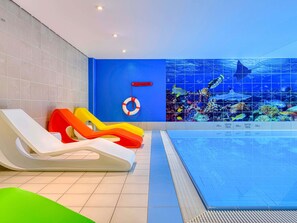 Un espace piscine avec des toboggans et une bouée de sauvetage fixée au mur.
