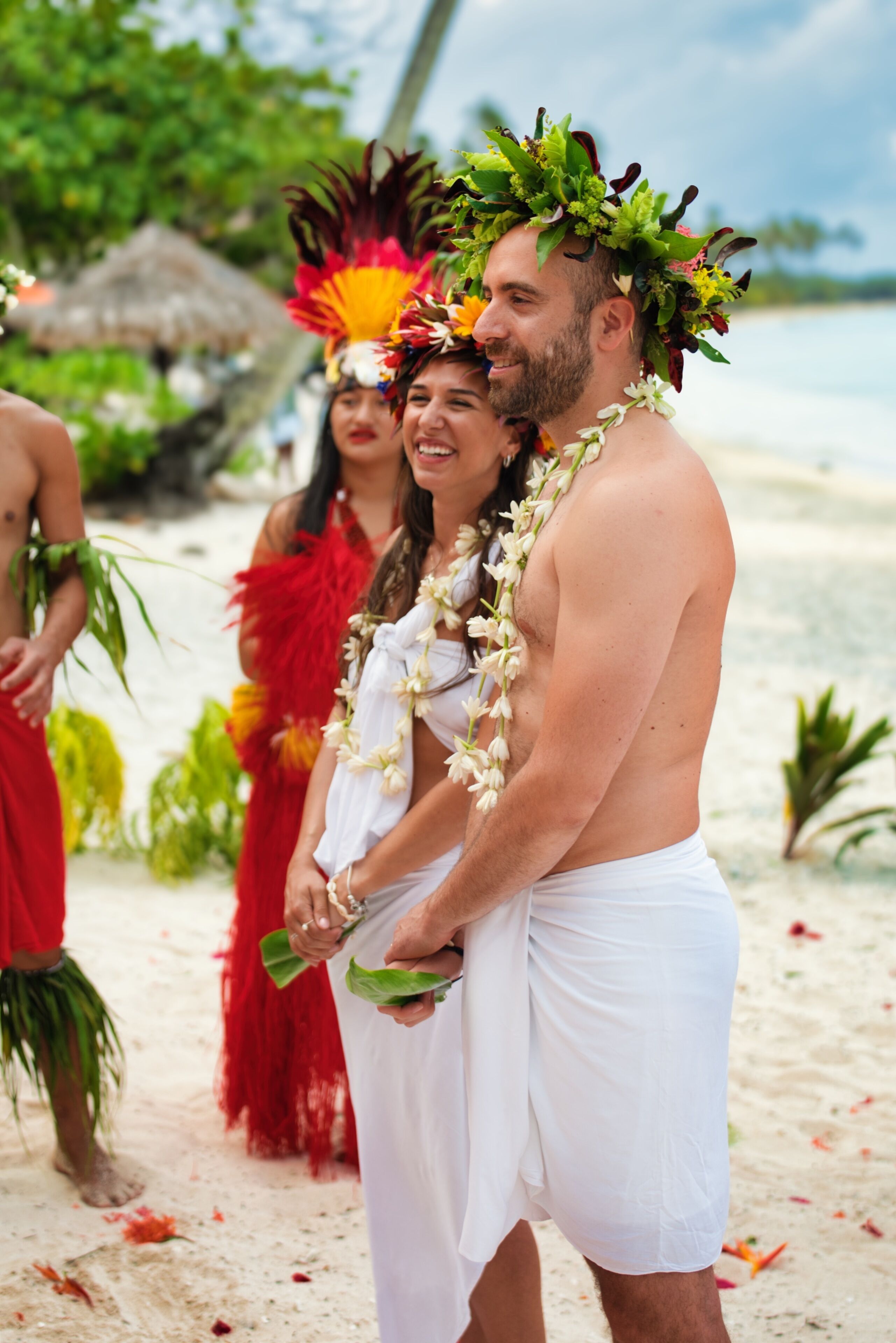 Une plage où l’on voit des personnes portant des vêtements traditionnels et des colliers de fleurs.