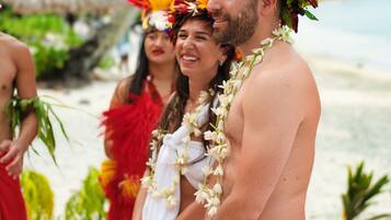 Une plage où l’on voit des personnes portant des vêtements traditionnels et des colliers de fleurs.
