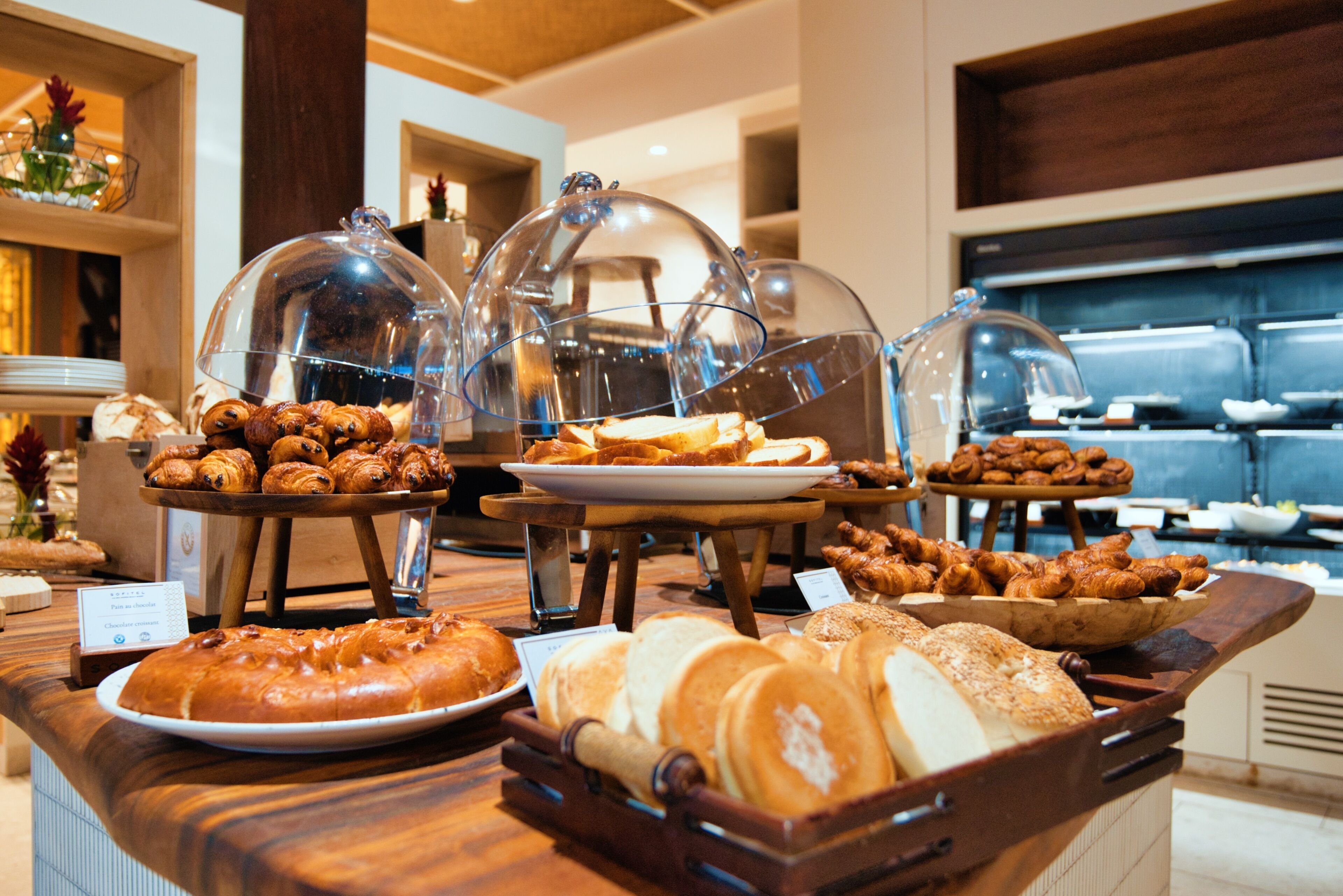 A buffet with various baked goods, including bread and pastries, displayed under glass domes.