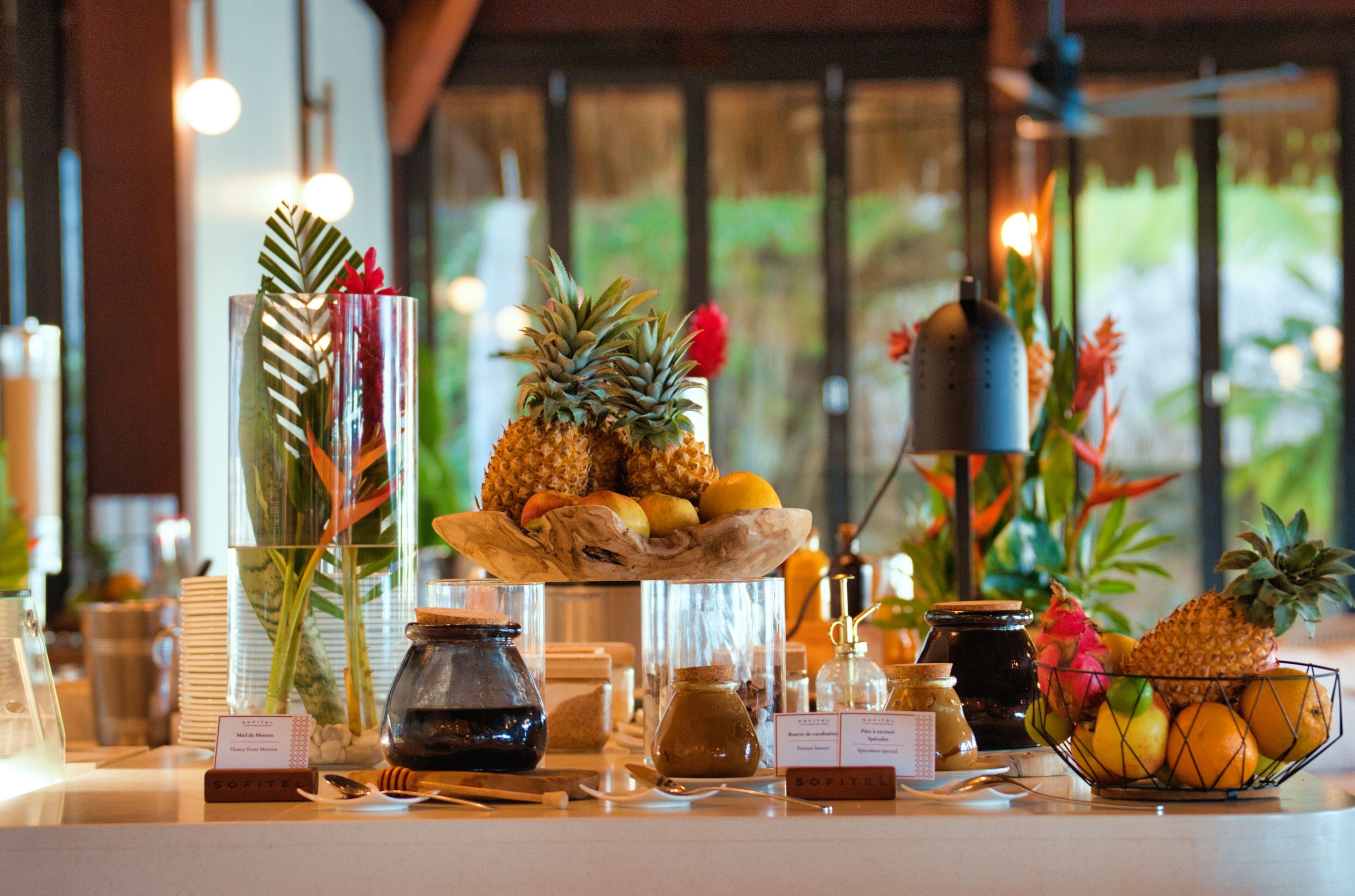A table with various food items and condiments, including a pineapple, apples, and jars of honey.