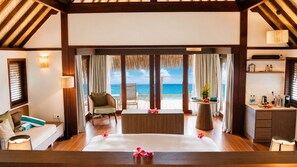 Une chambre avec un lit, une chaise, une table et une vue sur l’océan.