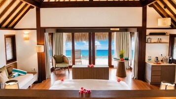 A room with a bed, a chair, a table, and a view of the ocean.