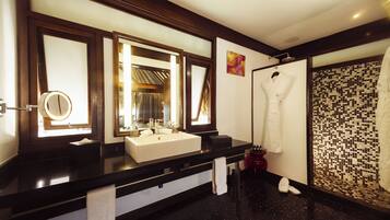 A hotel bathroom with a black countertop, a white sink, a mirror, and a shower area.