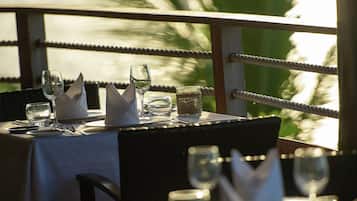 Une table dressée pour le dîner, avec vue sur la mer et les palmiers.