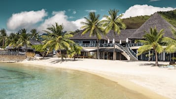 A beachfront resort with multiple overwater bungalows, palm trees, and clear turquoise waters.