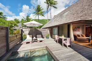A wooden deck with a pool, lounge chairs, a table, and a sofa.