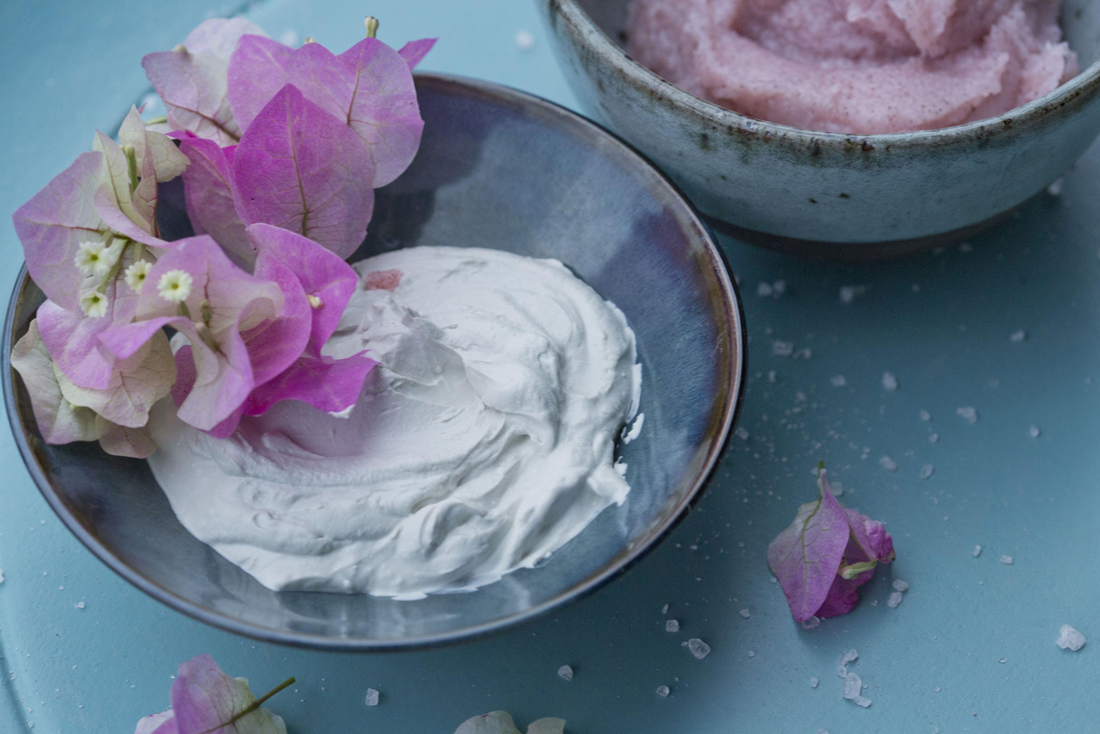 A bowl of pink substance, possibly a dessert, with a plate of white cream beside it.