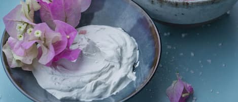 A bowl of pink substance, possibly a dessert, with a plate of white cream beside it.