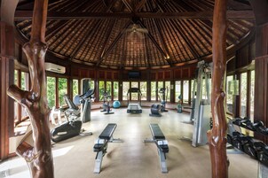 Un gimnasio con equipo de ejercicio, bancos y un techo de vigas de madera.